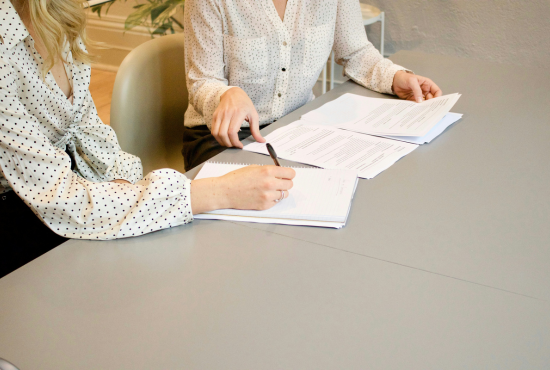 Deux femmes signant des documents officiels pour illustrer l'article indiquant les informations à indiquer sur son site internet
