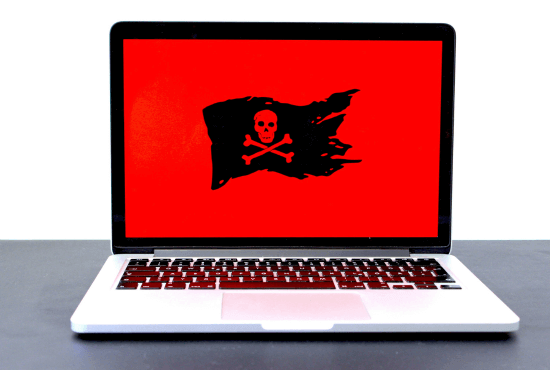 Vue sur un écran d'ordinateur portable avec un fond rouge sur l'écran et une tête de mort sur un drapeau noir